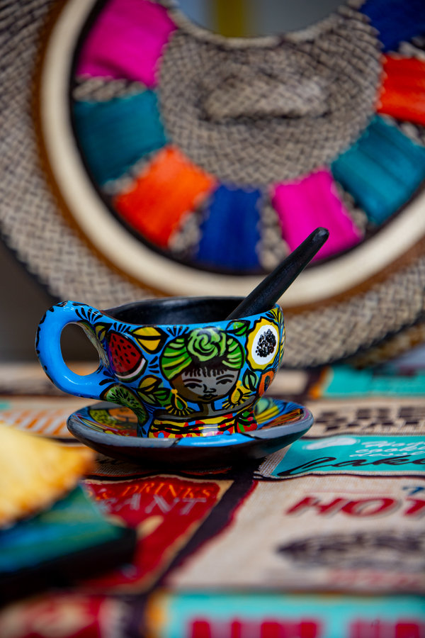 Tasse artisanale colombienne devant un panier tissé multicolore